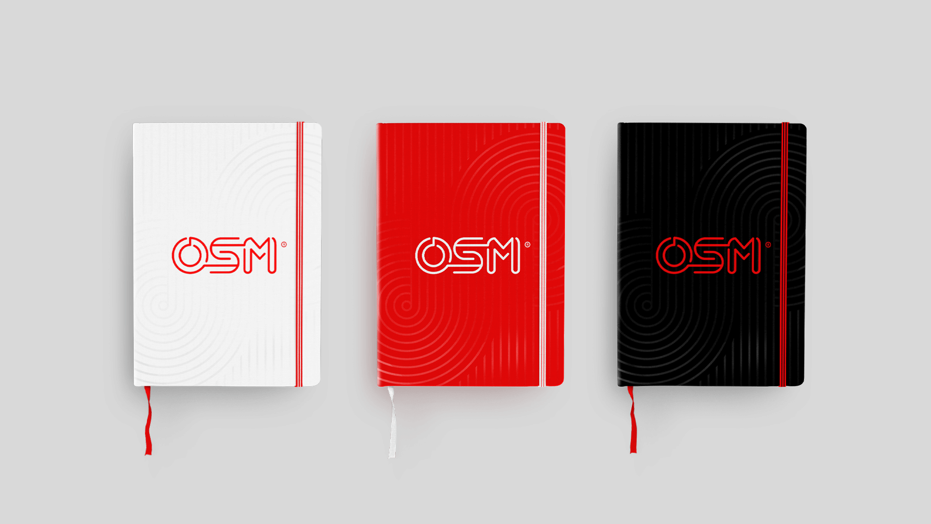 Three notebooks featuring a stylized "OSM" logo and spiral pattern design.