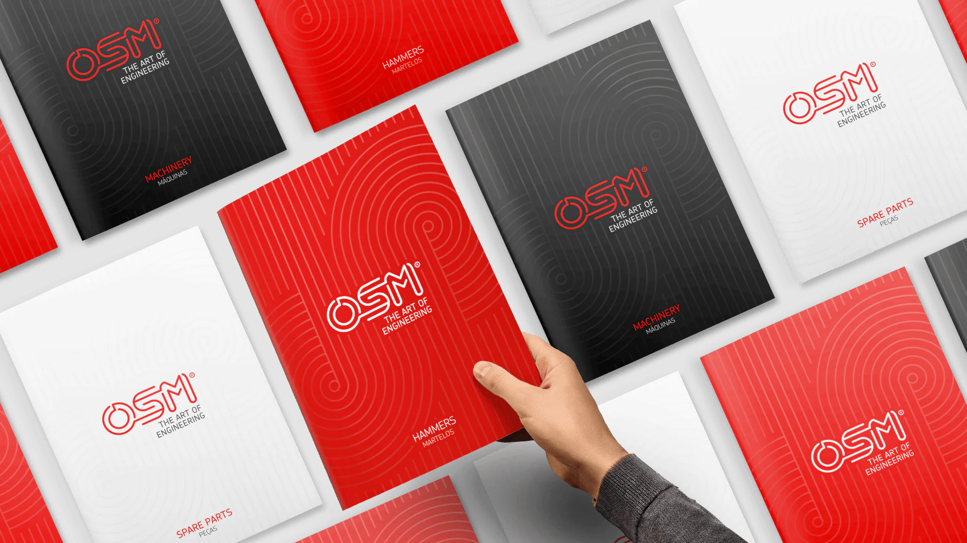 A hand reaches for a red brochure titled "HAMMERS," surrounded by various OSM engineering booklets.